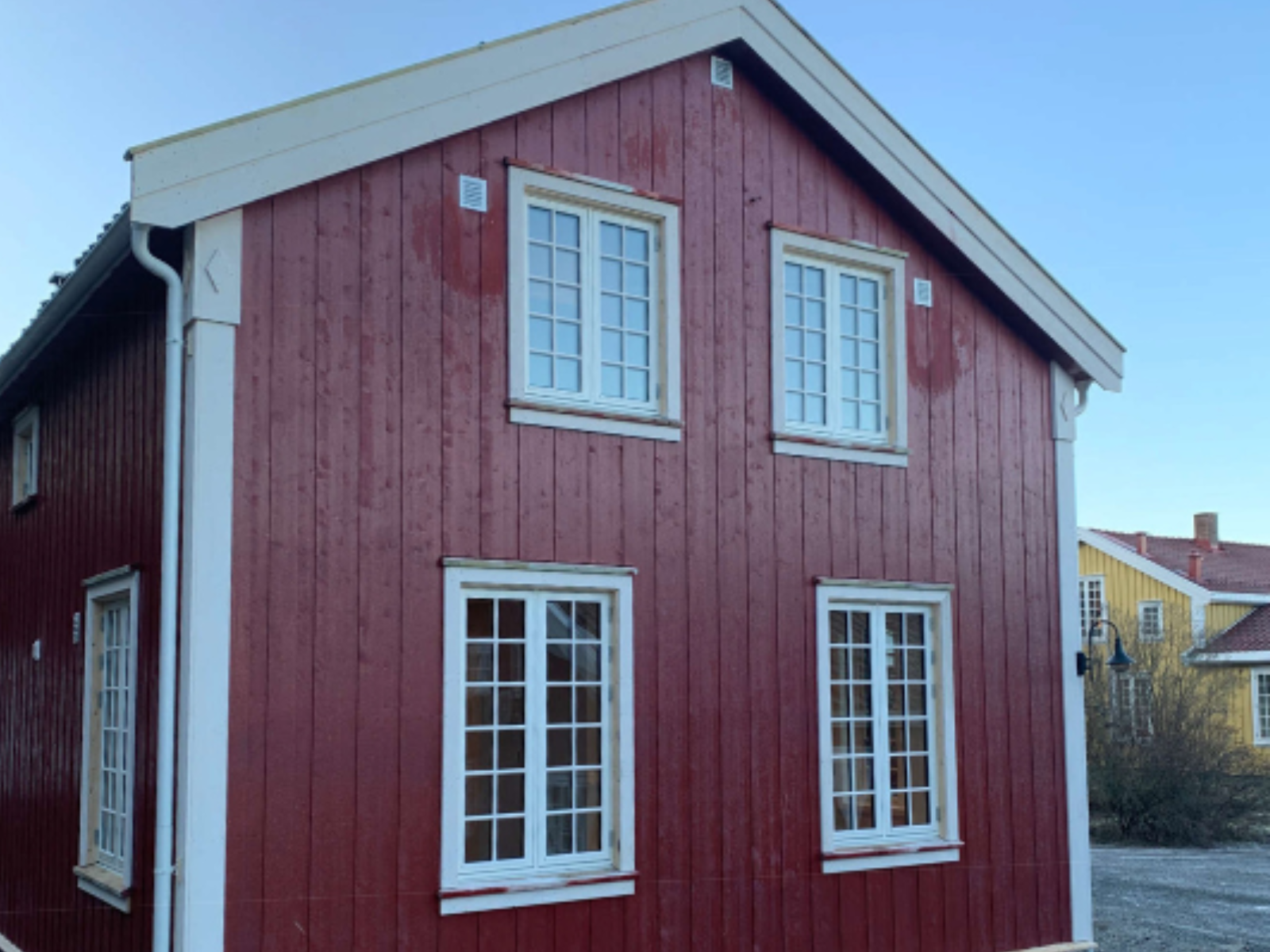 Rødt trehus med store tre/alu vinduer med sprosser